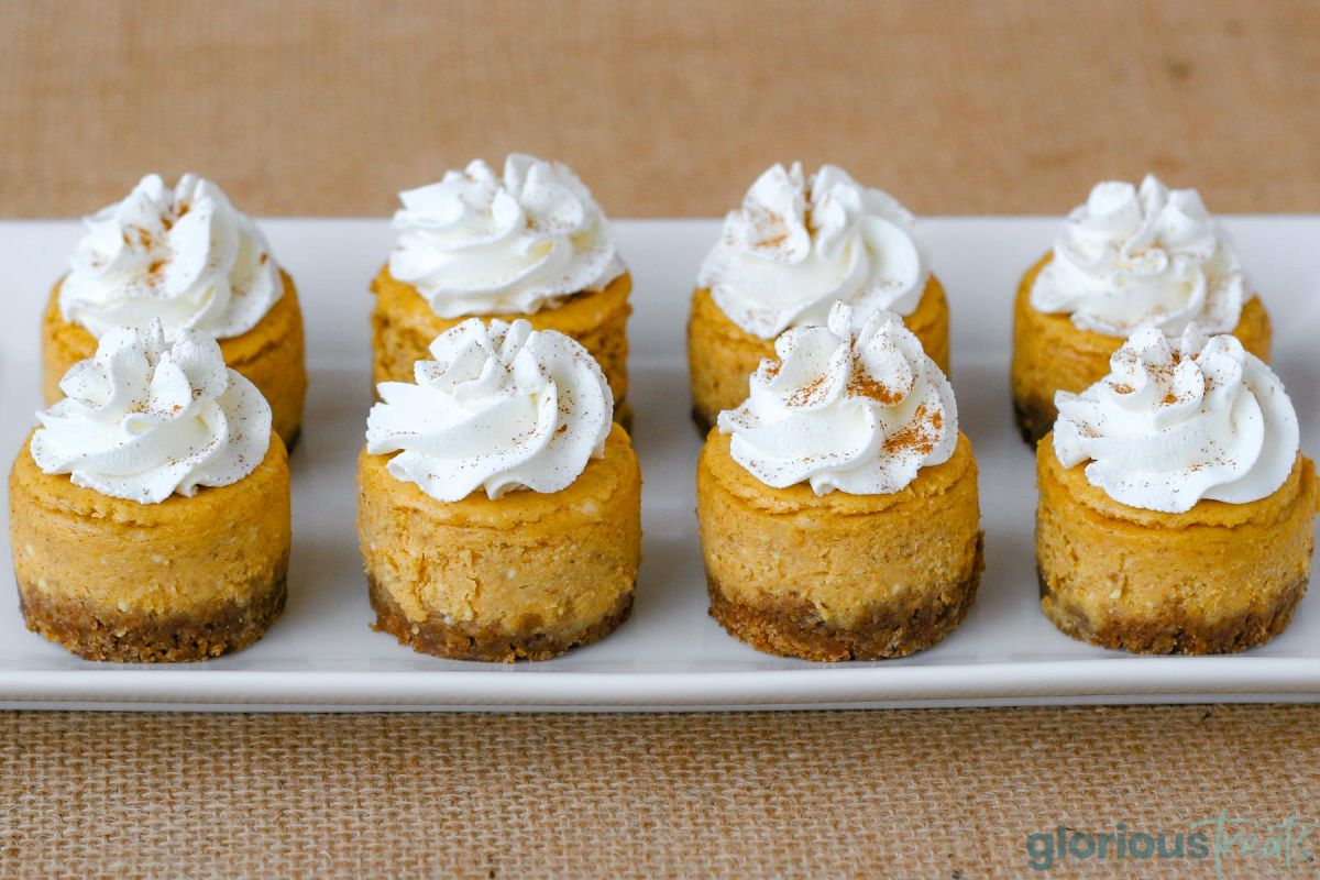 Eight mini pumpkin cheesecakes on a white rectangular platter.