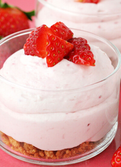 strawberry cheesecake mousse with graham cracker layer in small glass jar topped with fresh diced strawberries square
