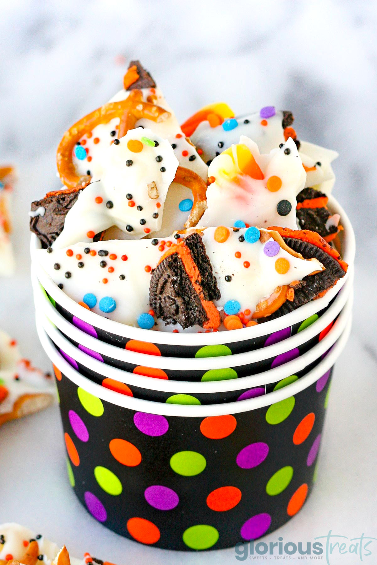 Close up look at halloween bark in a stack of colorful dotted paper cups.