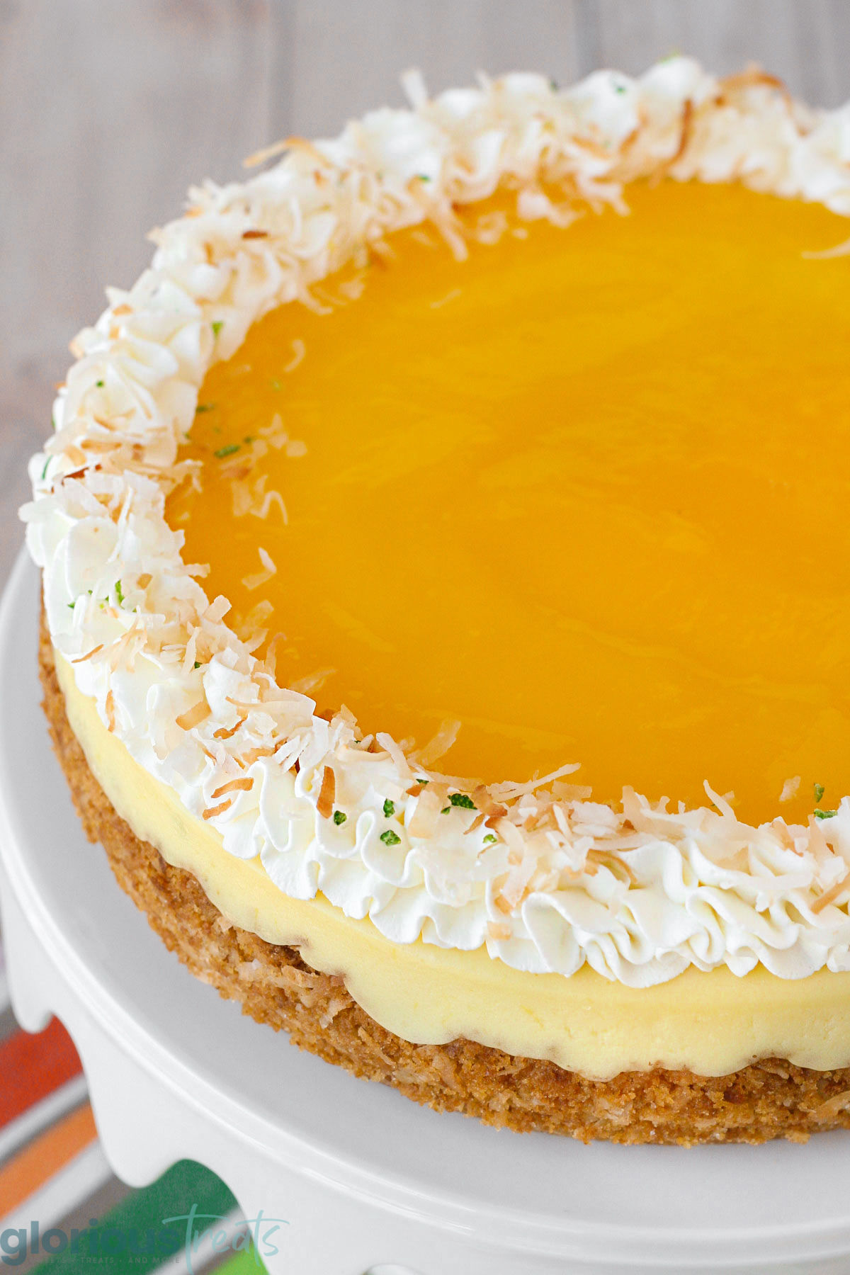 Angled top down view of mango lime cheesecake showing the mango lime glaze and fresh whipped cream along the edge.