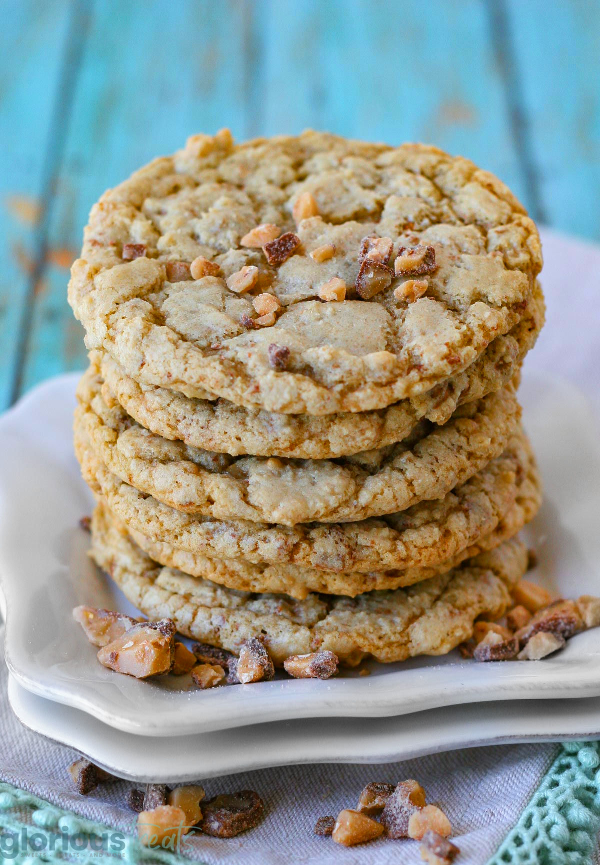 Five toffee cookies stacked on each other on white square plates.