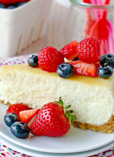 slice of cheesecake on white plate topped with fresh berries.