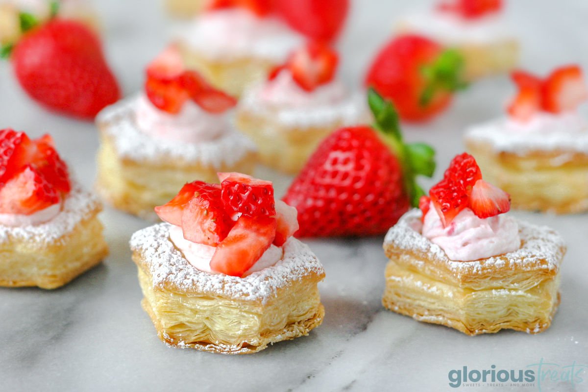 Strawberry Cream Puffs sitting on a marble surface topped  with fresh strawberries.