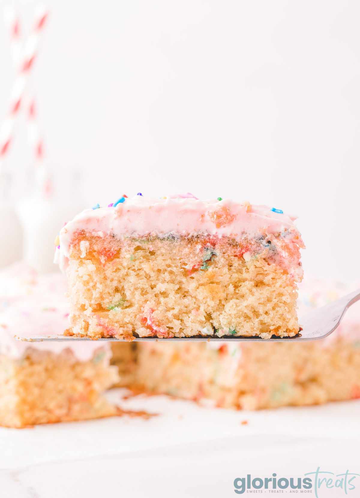 a slice of funfetti sheet cake being held up with a spatula.