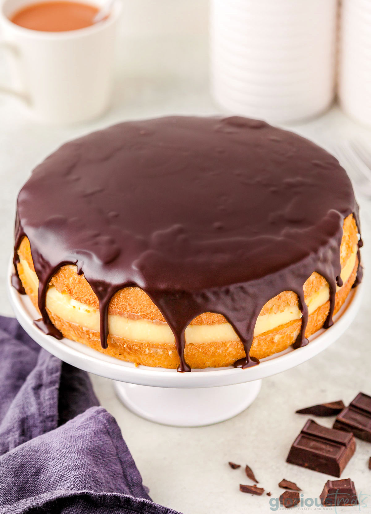 Top view of a boston cream pie on a white cake stand.