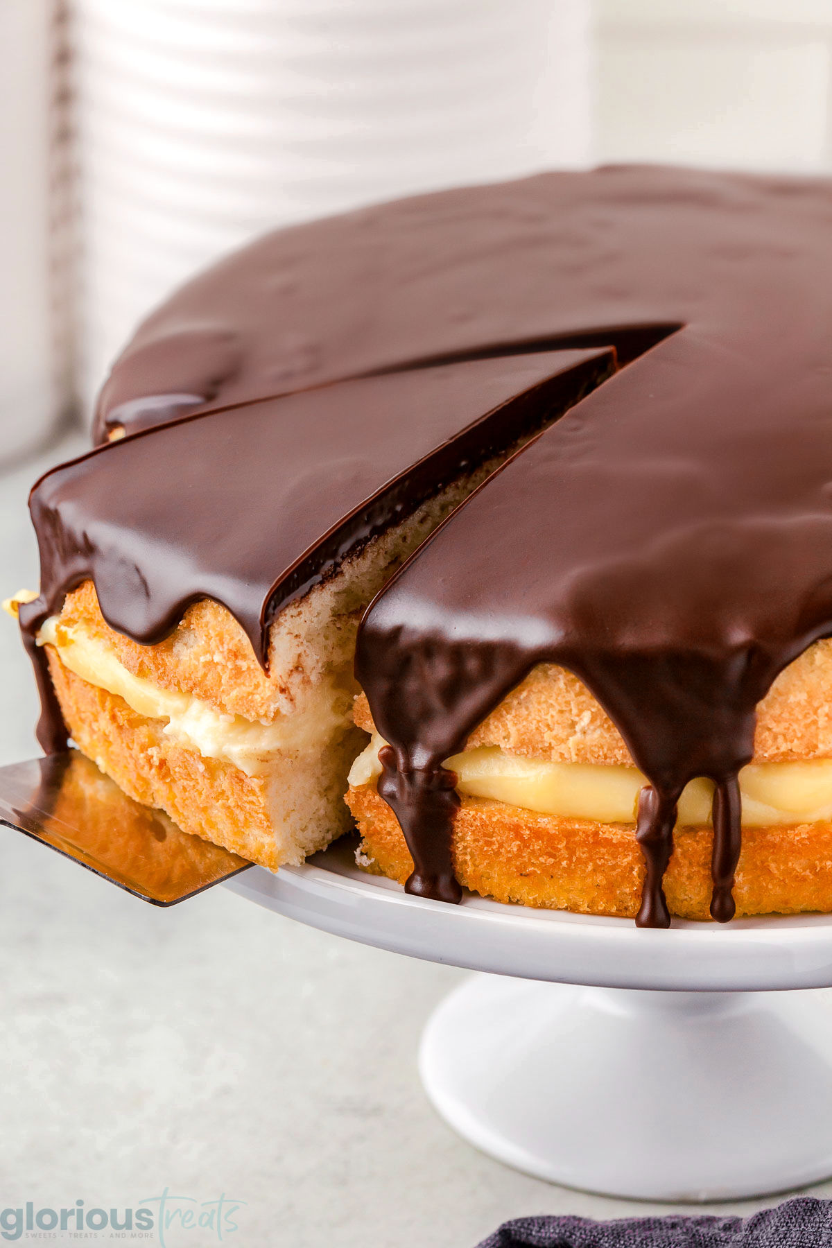 A spatula pulling a slice of boston cream pie out of the cake.