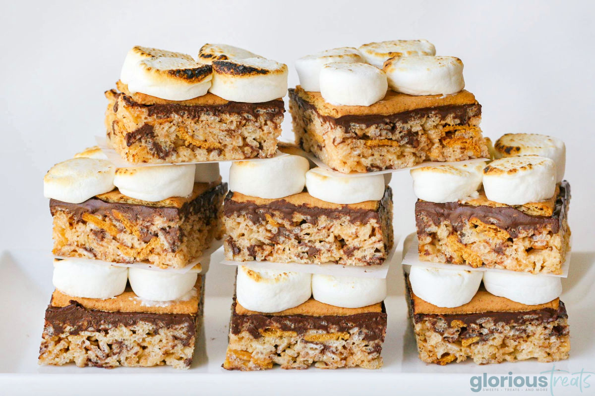 An impressive straight on view of 8 smores rice krispie treats stacked in a pyramid shape on a white surface.