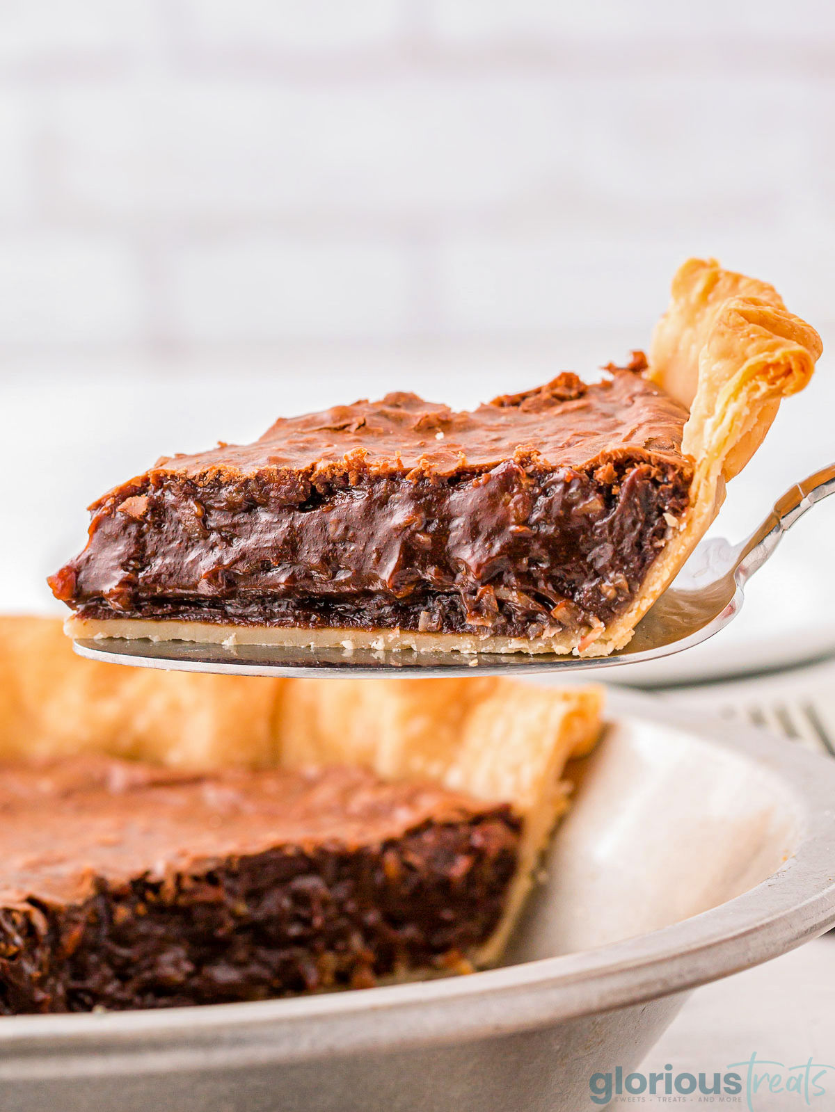 A spatula holding up a piece of german chocolate pie.