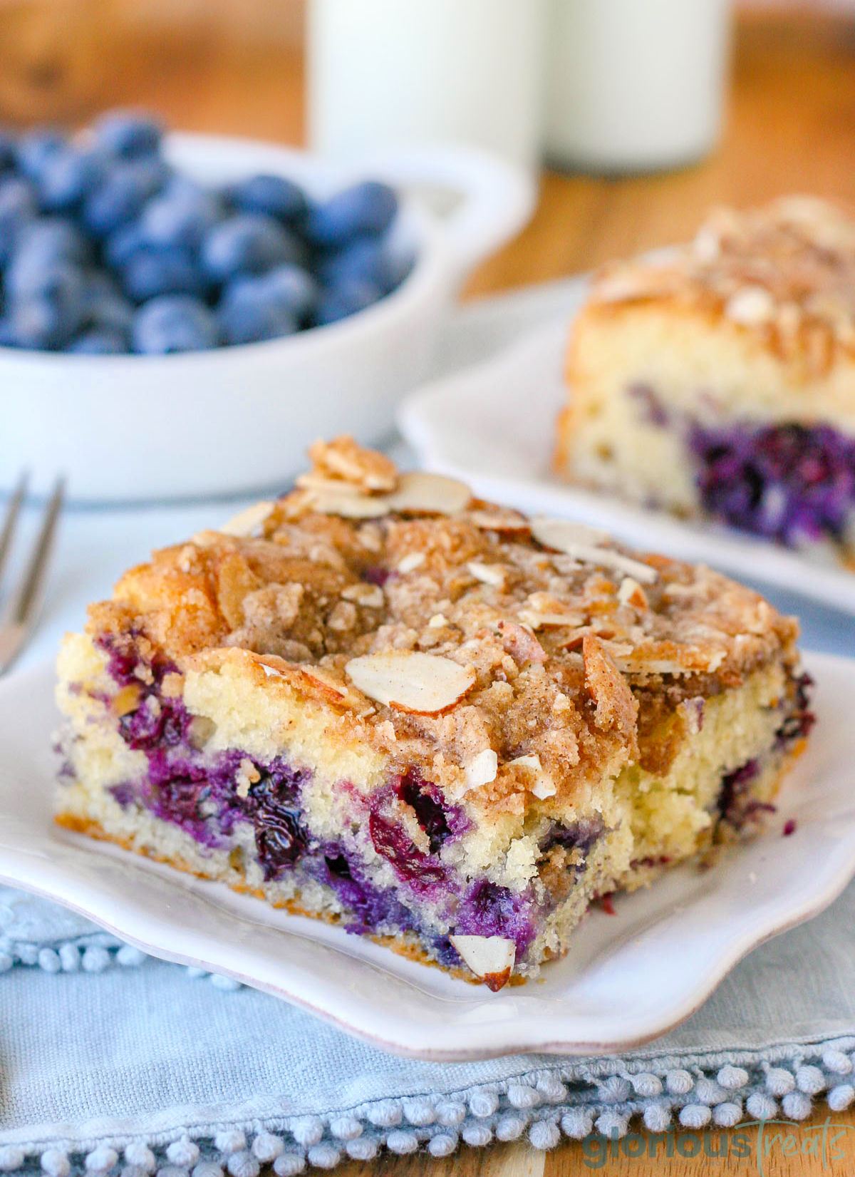 A slice of blueberry coffee cake on a white plate.