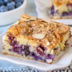 A slice of blueberry coffee cake on a white plate.