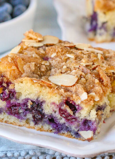 A slice of blueberry coffee cake on a white plate.