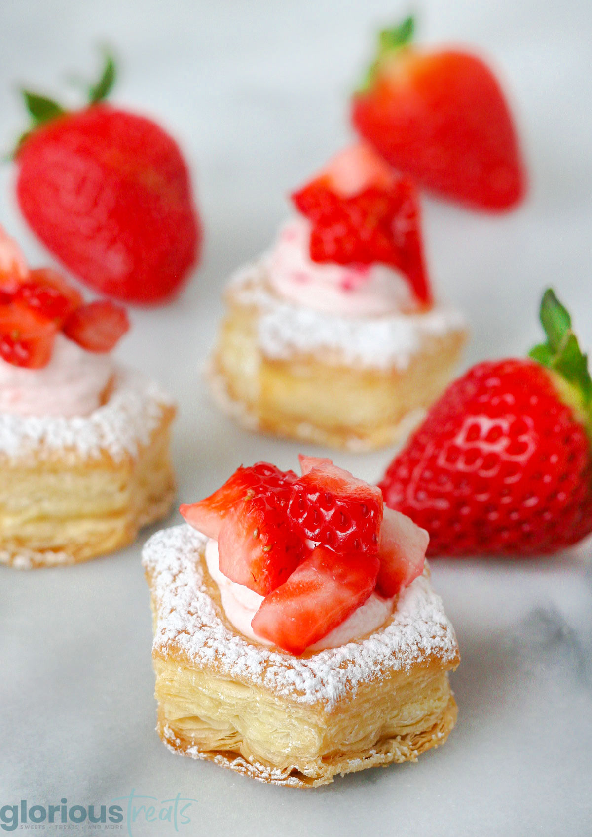 Strawberry Cream Puffs sitting on a marble surface topped with fresh strawberries.