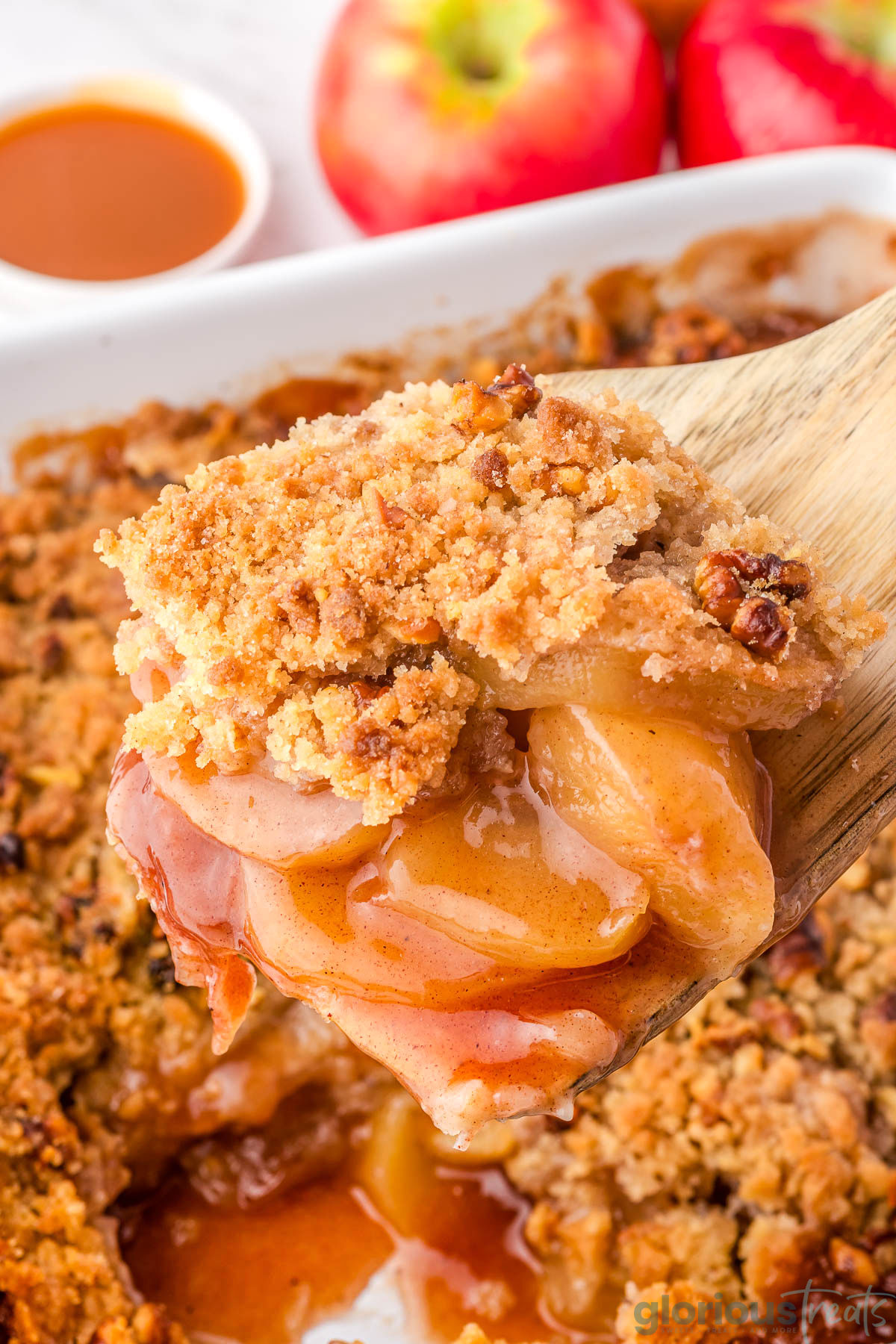 Close up view of a wood spatula holding up a serving of apple crumble.