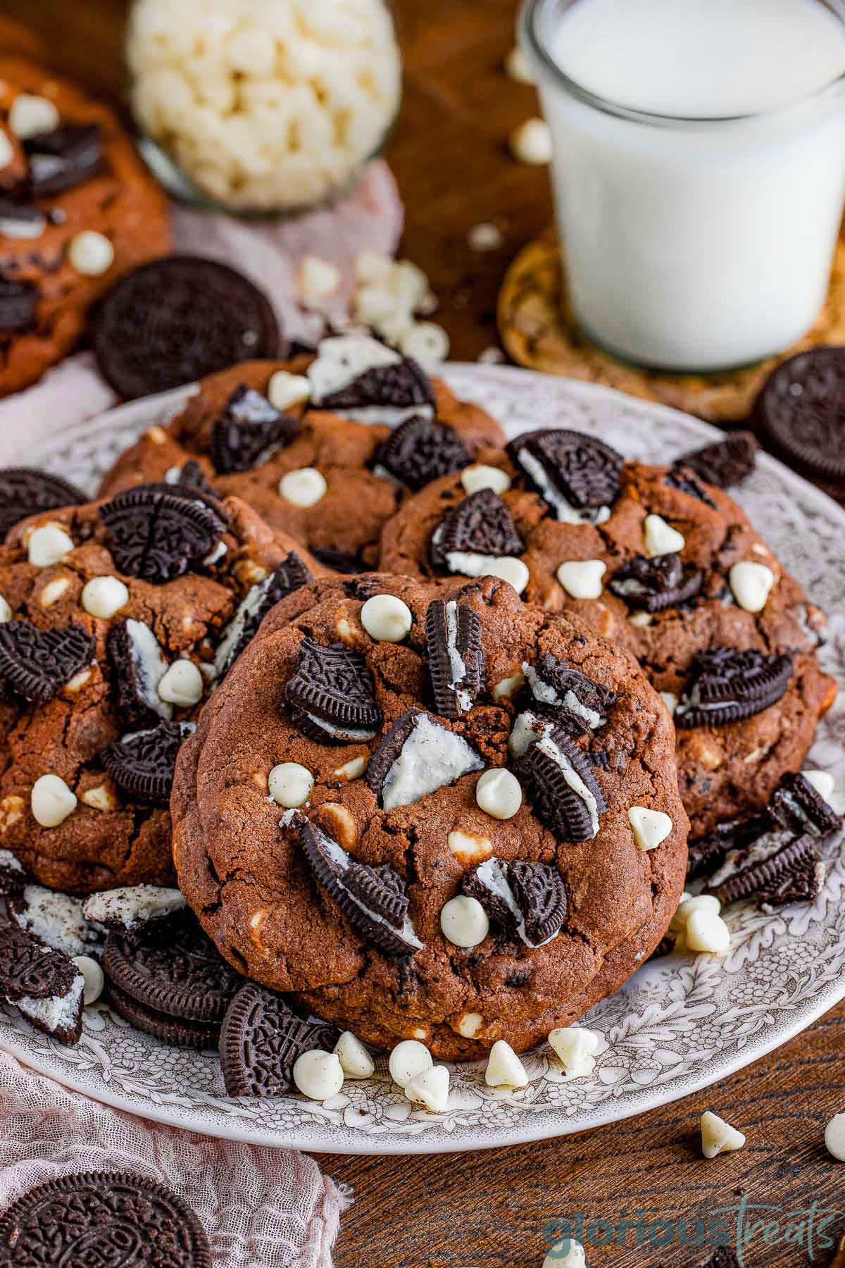 Cookies and cream cookies on a serving platter with a glass of milk in the background.