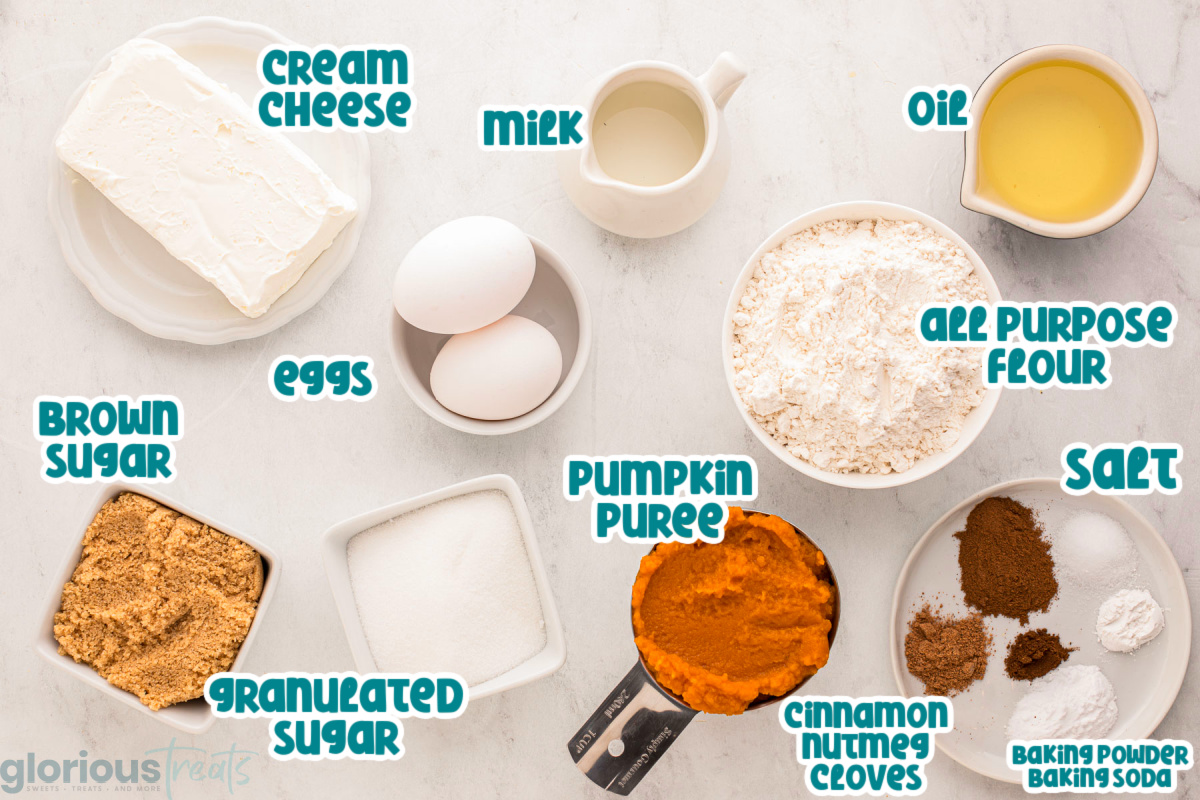 Ingredients for pumpkin cream cheese bread laid out on a marble surface. Each of the ingredients are labeled with blue and white text.