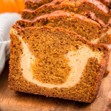 A close up view of a loaf of pumpkin cream cheese bread. The loaf is cut into slices.