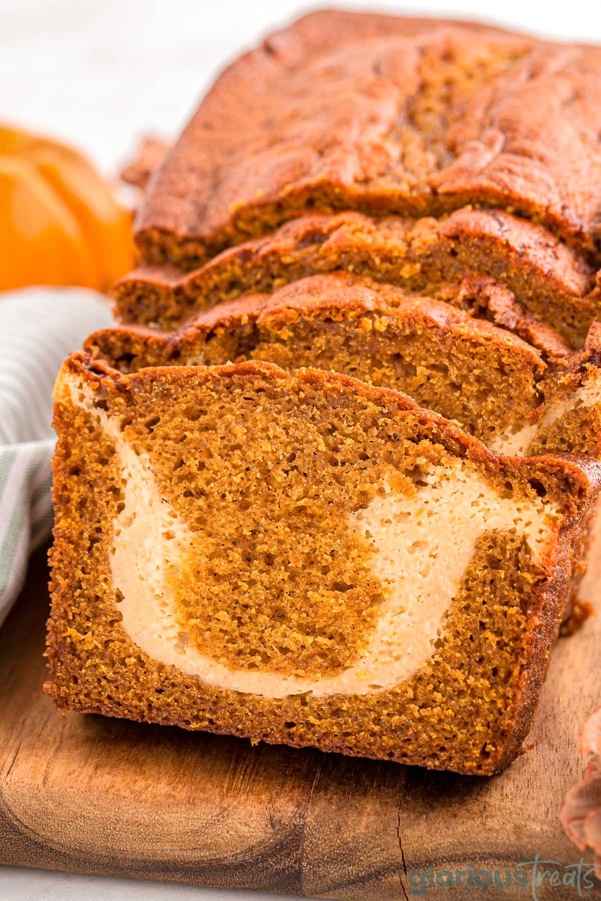 A close up view of a loaf of pumpkin cream cheese bread. The loaf is cut into slices.