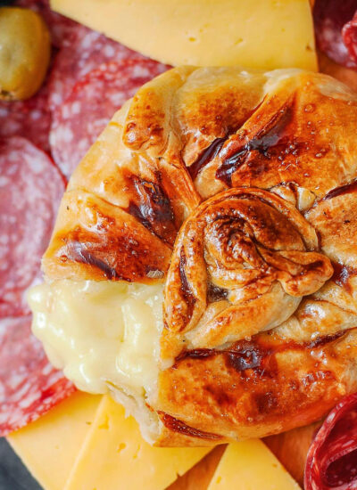 Honey baked brie wrapped in puff pastry. Salami and cheese are on the platter with the brie.