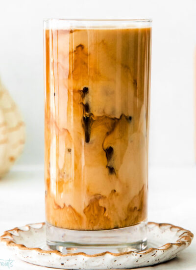 A glass of pumpkin cream cold brew on a decorative plate.