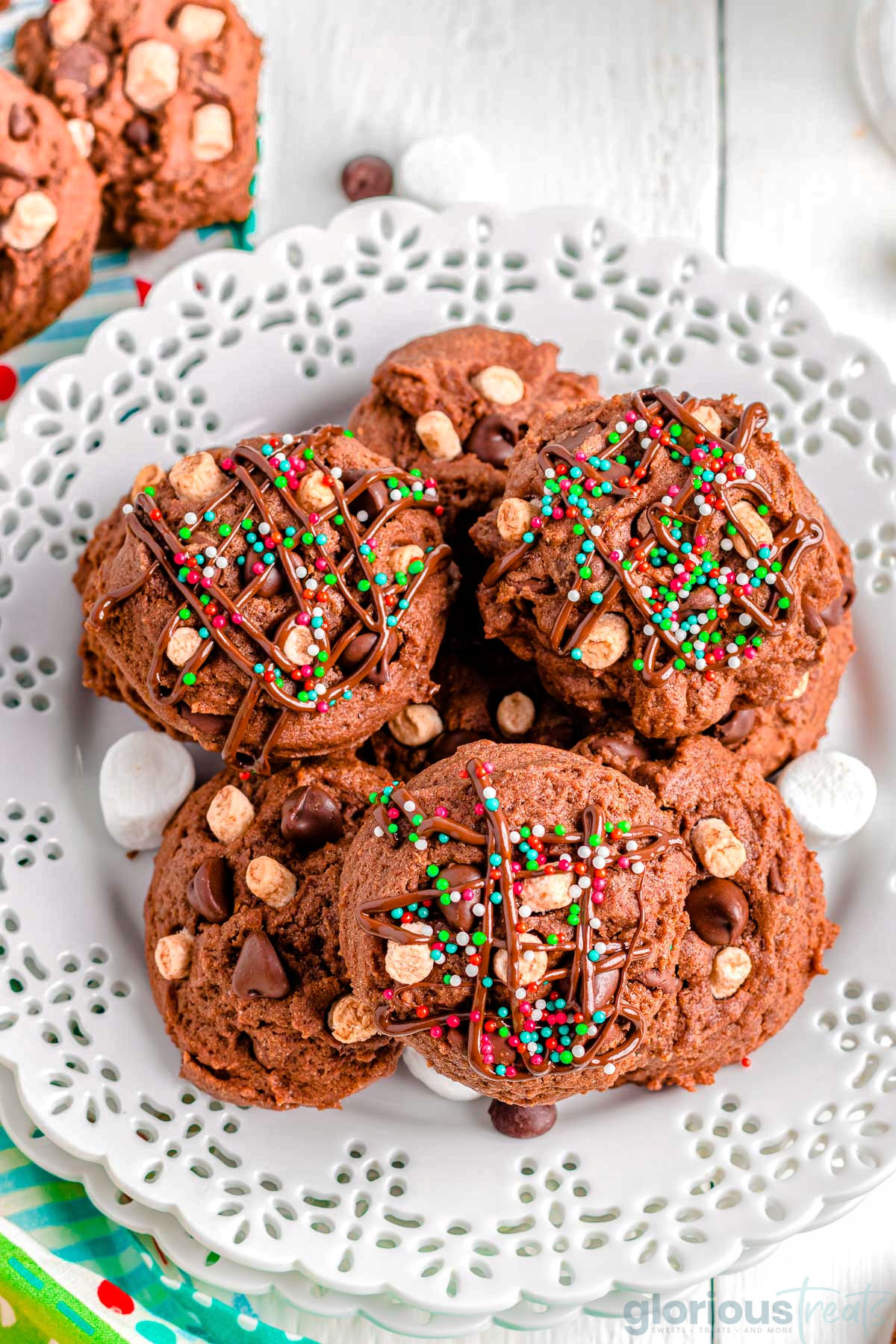 Top down view of hot chocolate cookies topped with melted chocolate and festive sprinkles.