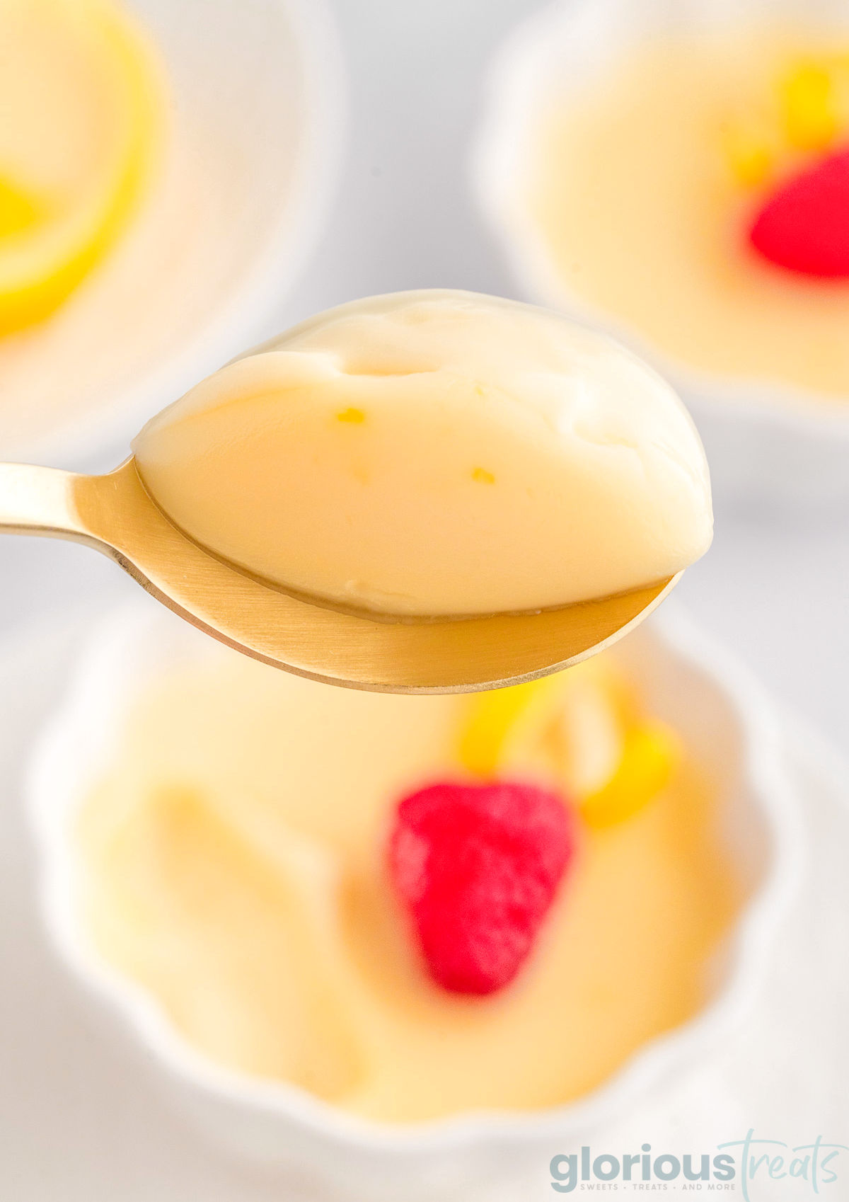 A close up of a spoon holding a spoonful of lemon posset above the dish.